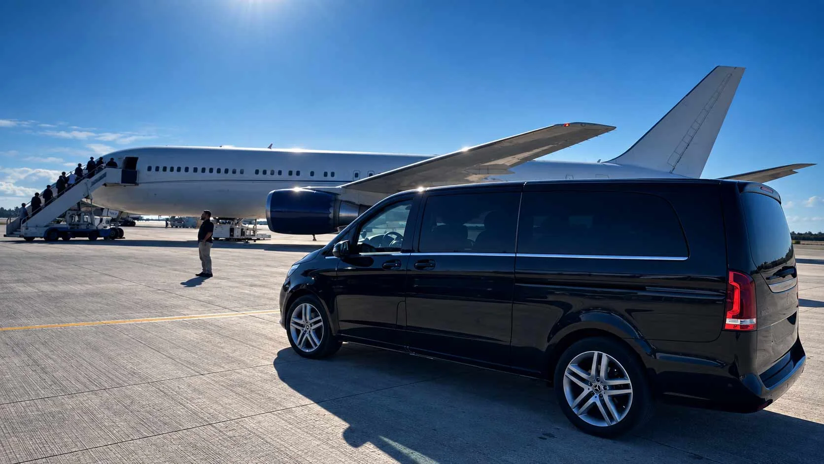 Mercedes nera accanto a un aereo sulla pista aeroportuale